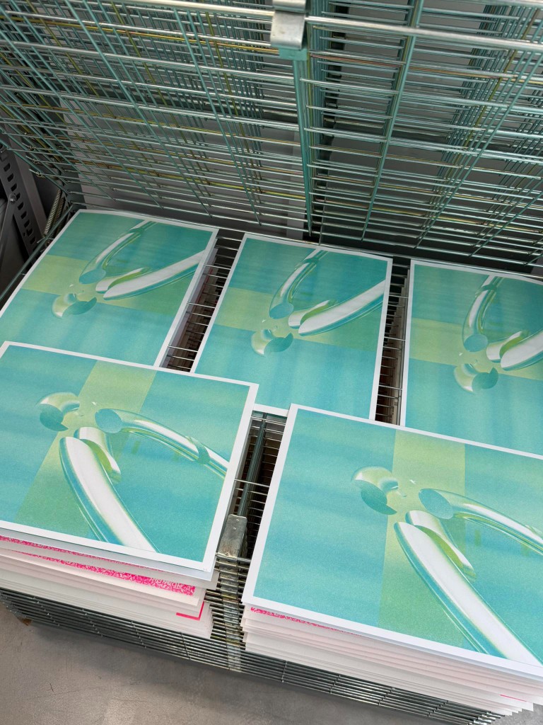 Teal prints drying on a rack